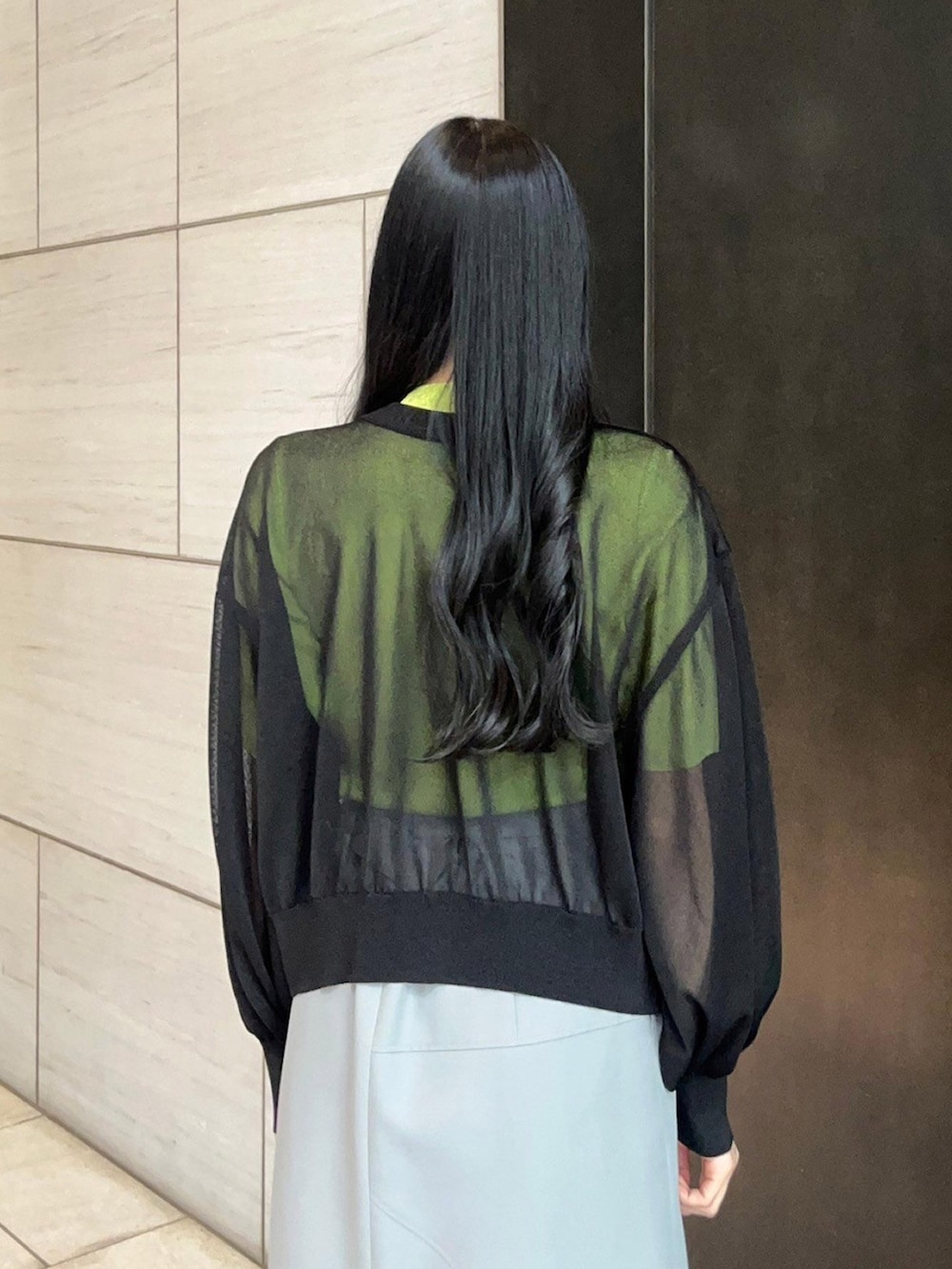 グレー系のスカート、ブラック系のカーディガン/ボレロ、グリーン系のニット/セーターを着用したレディースの春コーディネートの6枚目の写真