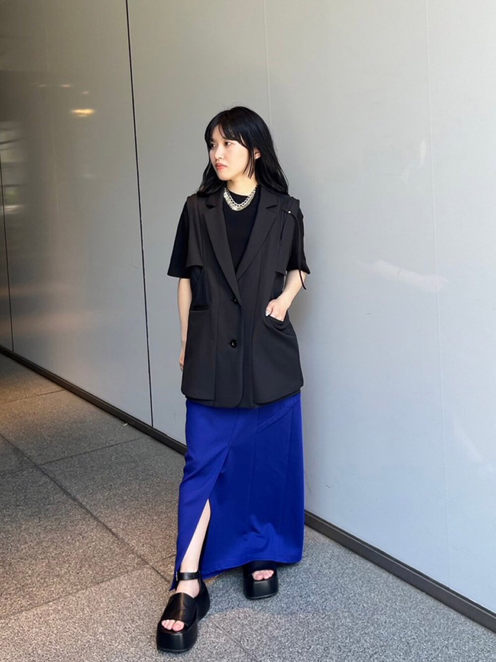 ブラック系のベスト、ブルー系のスカートを着用したレディースの夏コーディネートの2枚目の写真