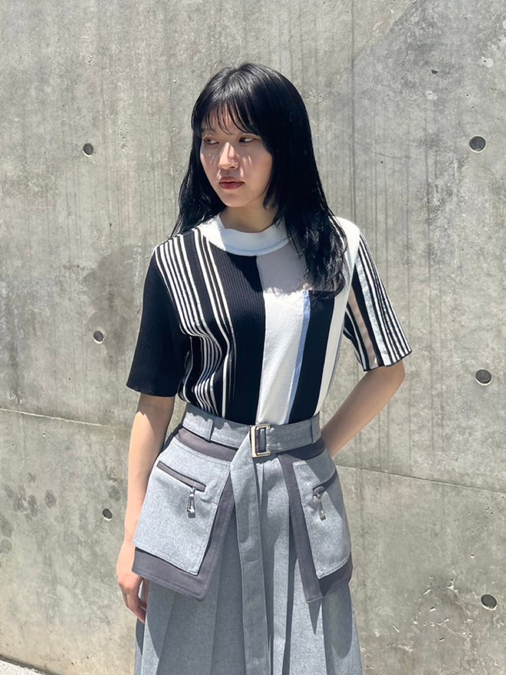 ブラック系のニット/セーター、グレー系のスカートを着用したレディースの夏コーディネートの3枚目の写真