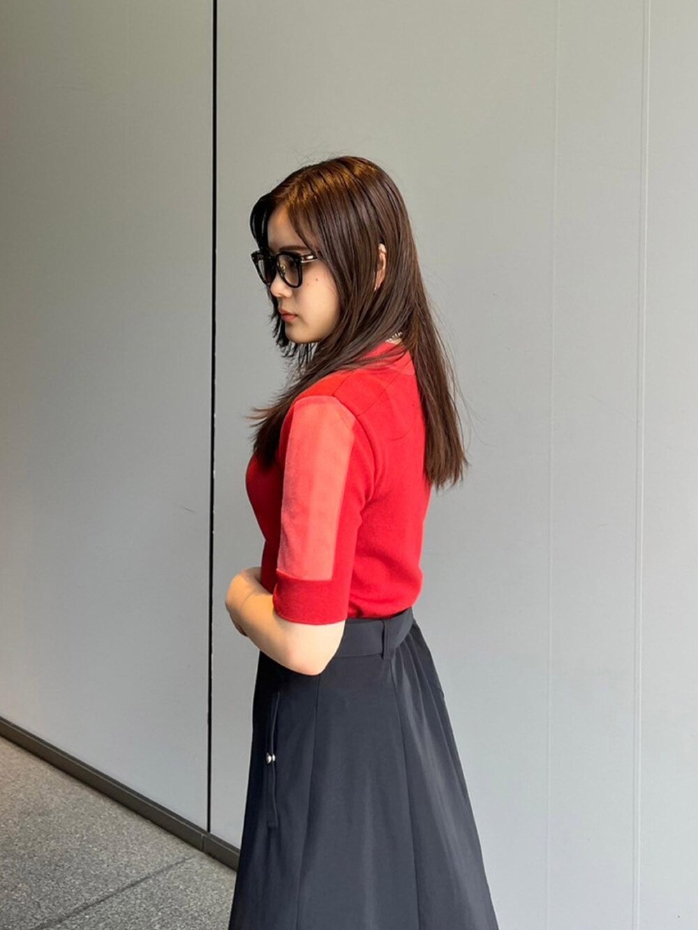 レッド系のニット/セーター、ブラック系のスカートを着用したレディースの夏コーディネートの5枚目の写真