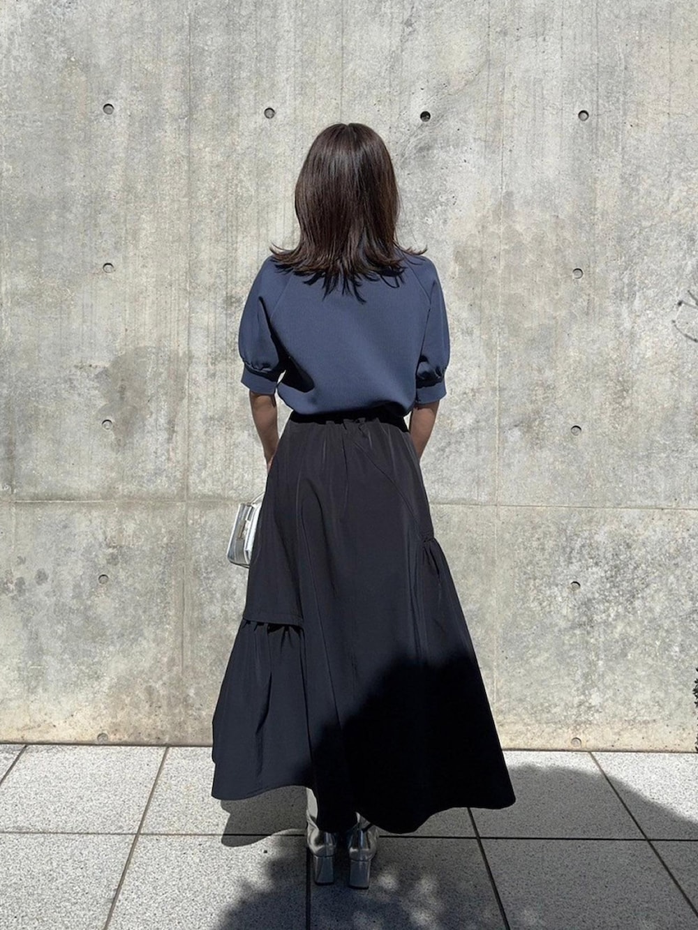 グレー系のニット/セーター、ブラック系のスカートを着用したレディースの春コーディネートの3枚目の写真