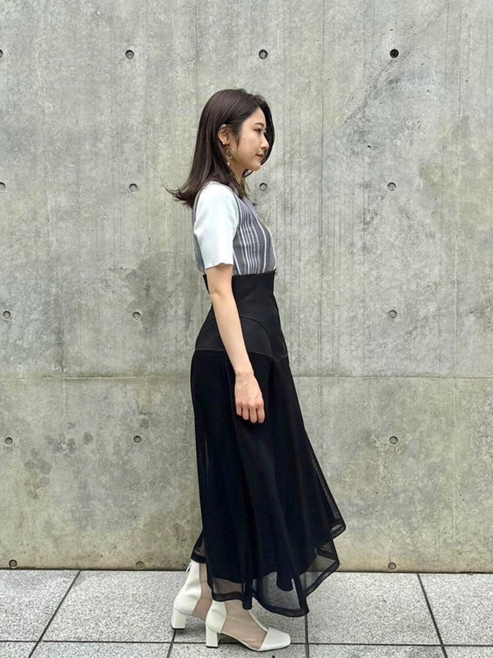 イエロー系のニット/セーター、ブラック系のスカートを着用したレディースの春コーディネートの4枚目の写真