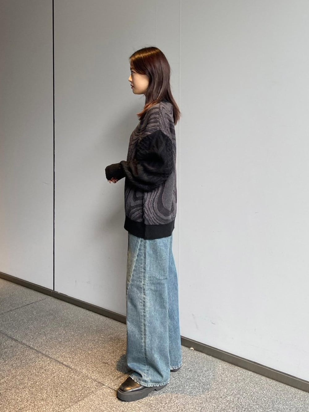 ブラック系のニット/セーター、ブルー系のデニムパンツを着用したレディースの秋コーディネートの2枚目の写真