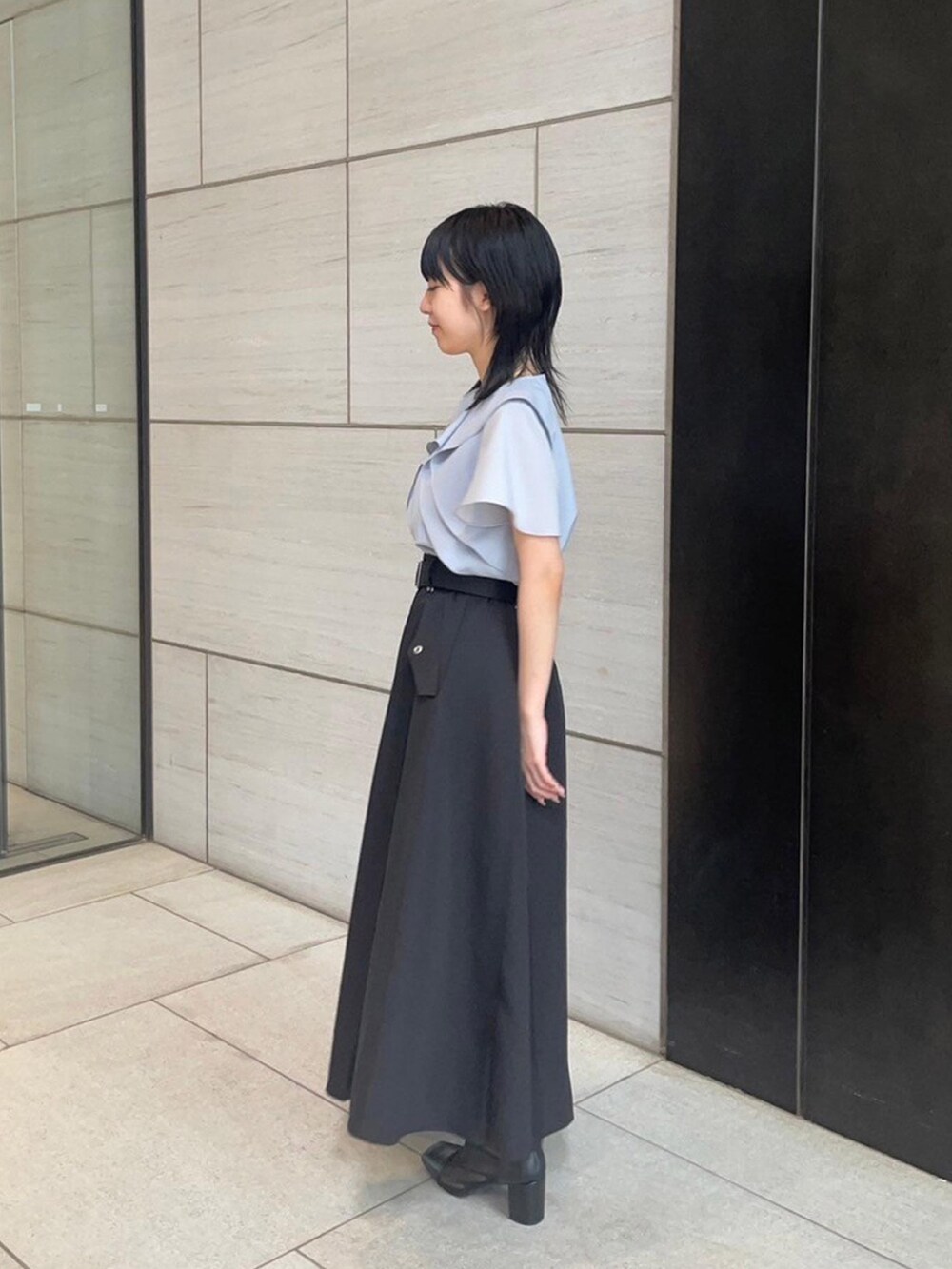 ブルー系のシャツ/ブラウス、ブラック系のスカートを着用したレディースの春コーディネートの2枚目の写真