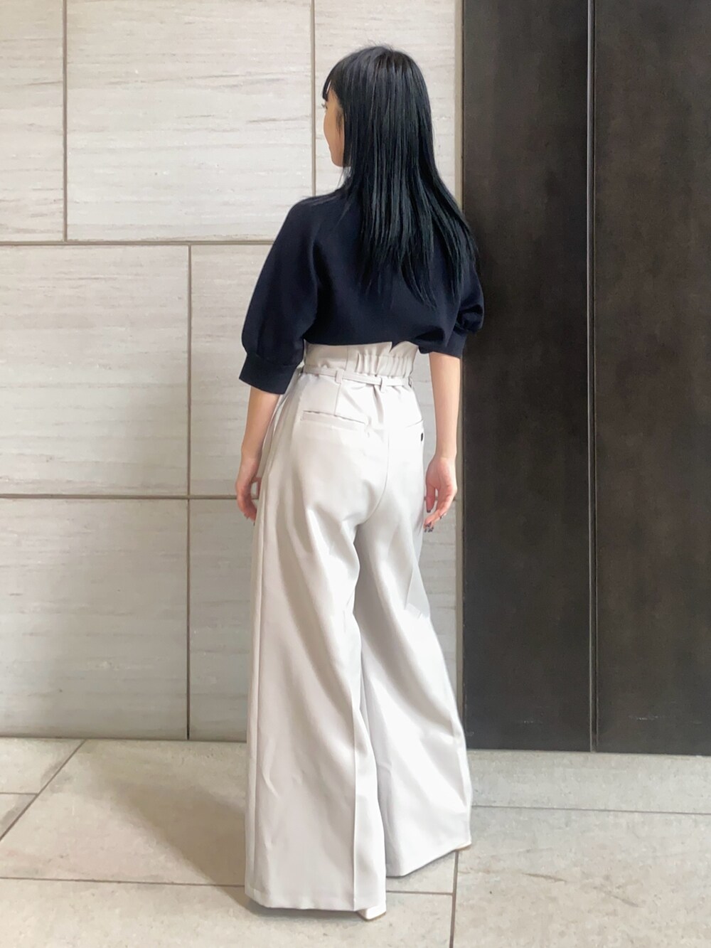 ブラック系のニット/セーター、グレー系のスラックスを着用したレディースの春コーディネートの2枚目の写真