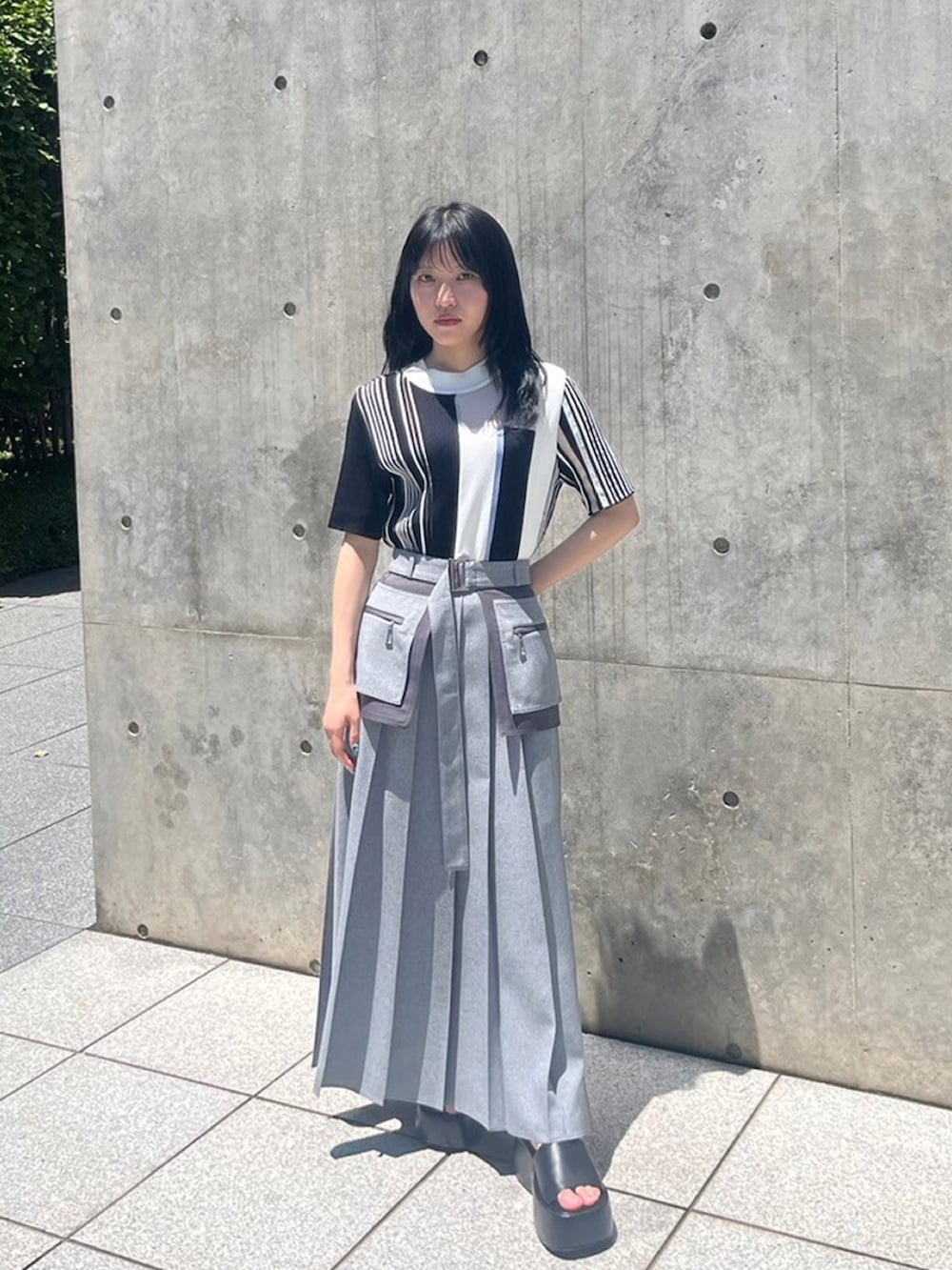ブラック系のニット/セーター、グレー系のスカートを着用したレディースの夏コーディネートの2枚目の写真