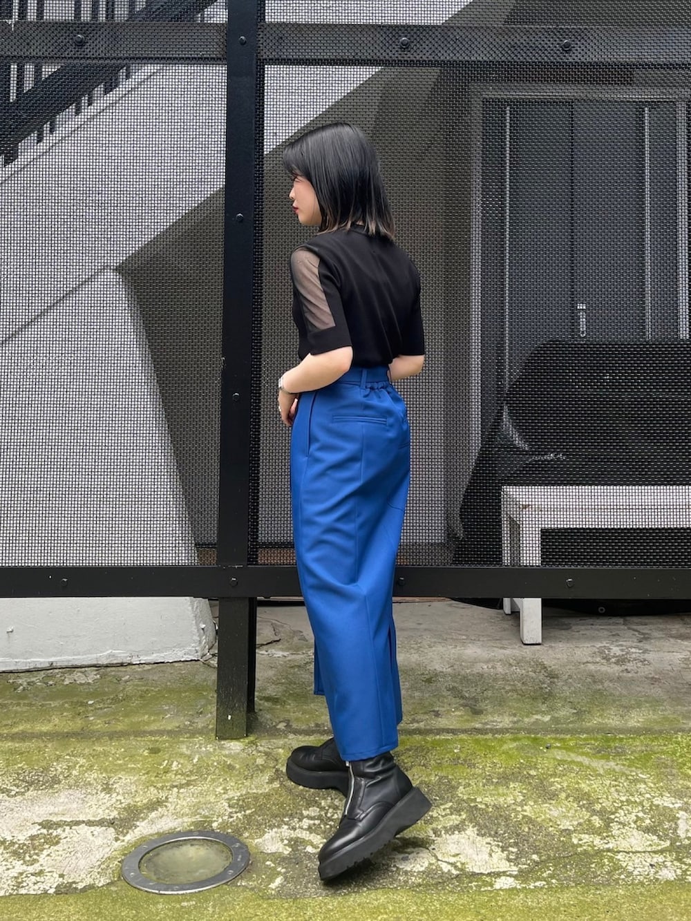 ブラック系のニット/セーター、ブルー系のスカートを着用したレディースの春コーディネートの3枚目の写真