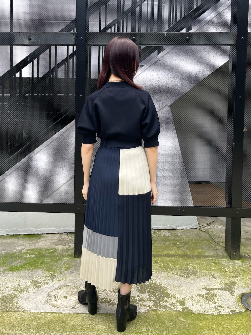 ブラック系のニット/セーター、ブルー系のスカート、ブラック系のブーツを着用したレディースの春コーディネートの4枚目の写真