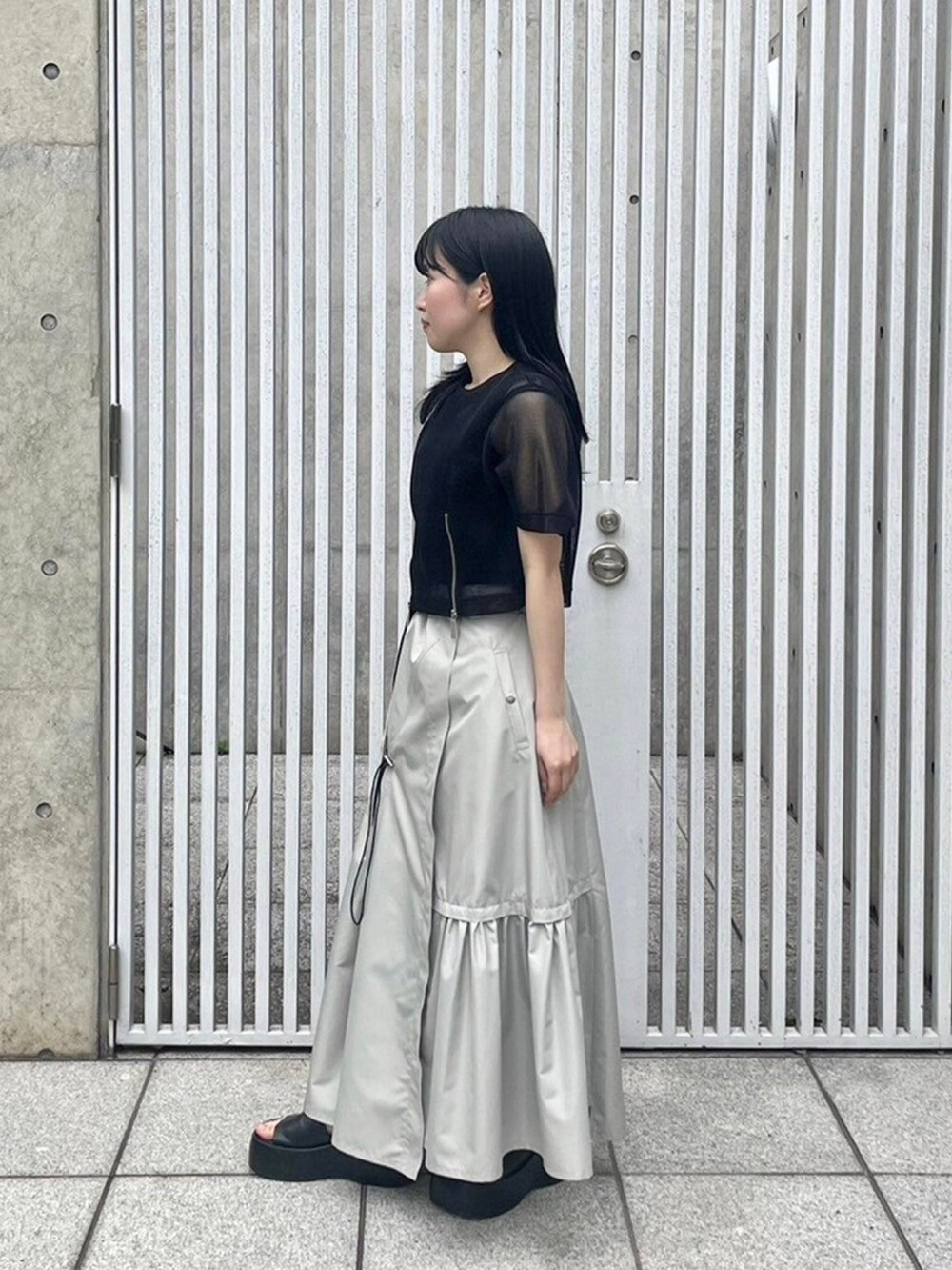 ブラック系のシャツ/ブラウス、ベージュ系のスカート、ブラック系のタンクトップを着用したレディースの春コーディネートの2枚目の写真