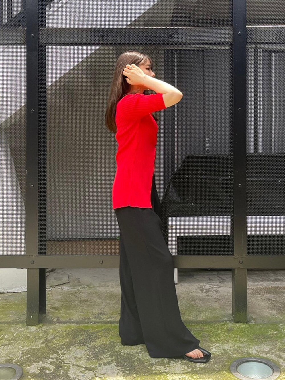 ブラック系のスラックス、レッド系のニット/セーターを着用したレディースの春コーディネートの2枚目の写真