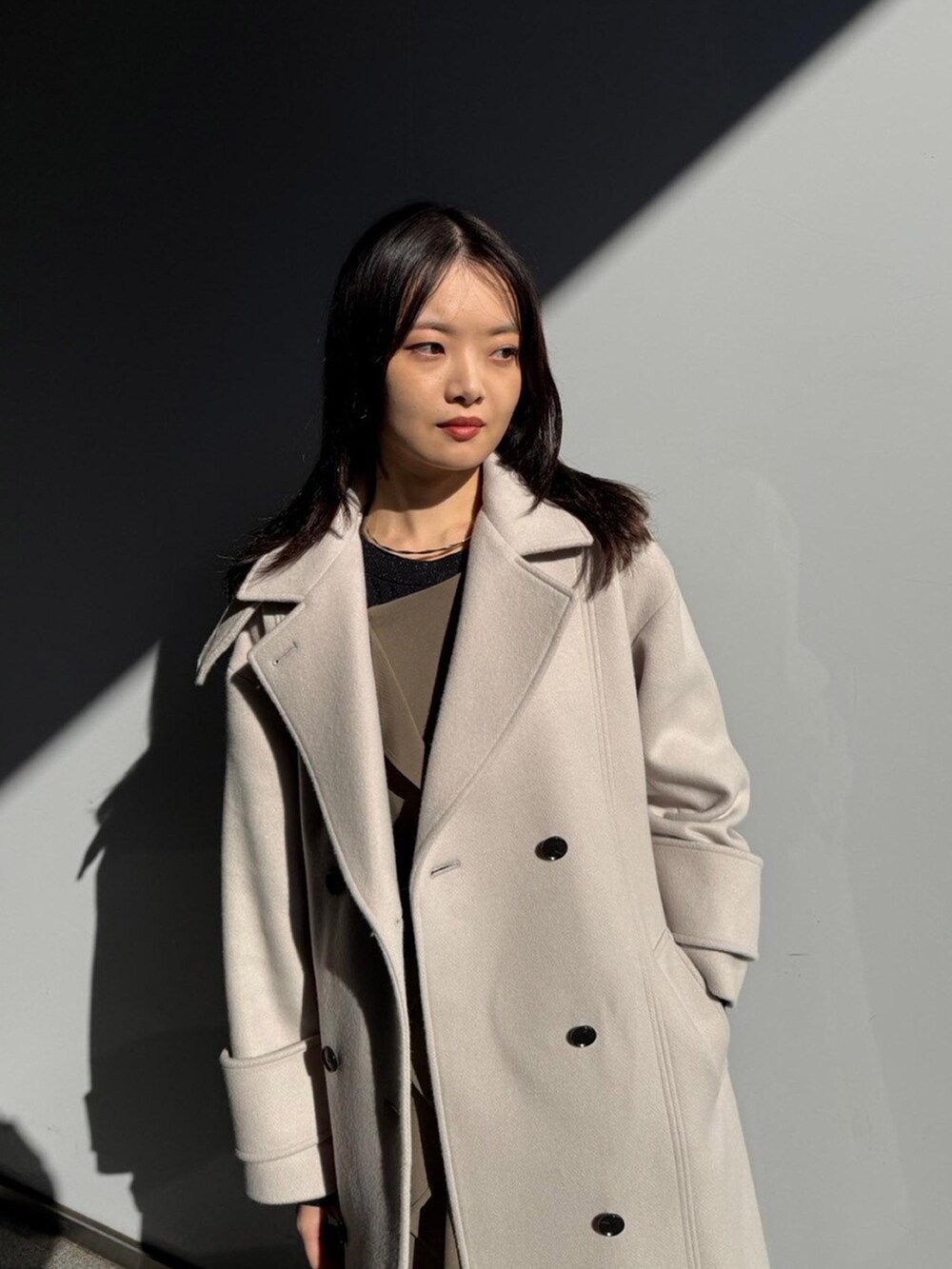 ホワイト系のステンカラーコートを着用したレディースの秋コーディネートの4枚目の写真