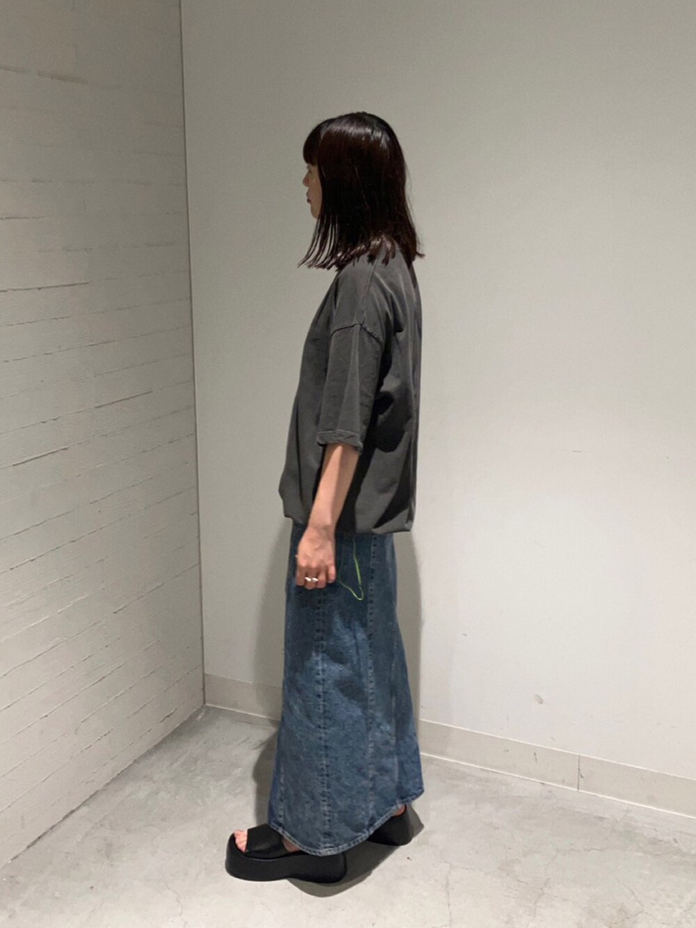 グレー系のTシャツ/カットソー、ブルー系のデニムスカートを着用したレディースの夏コーディネートの2枚目の写真