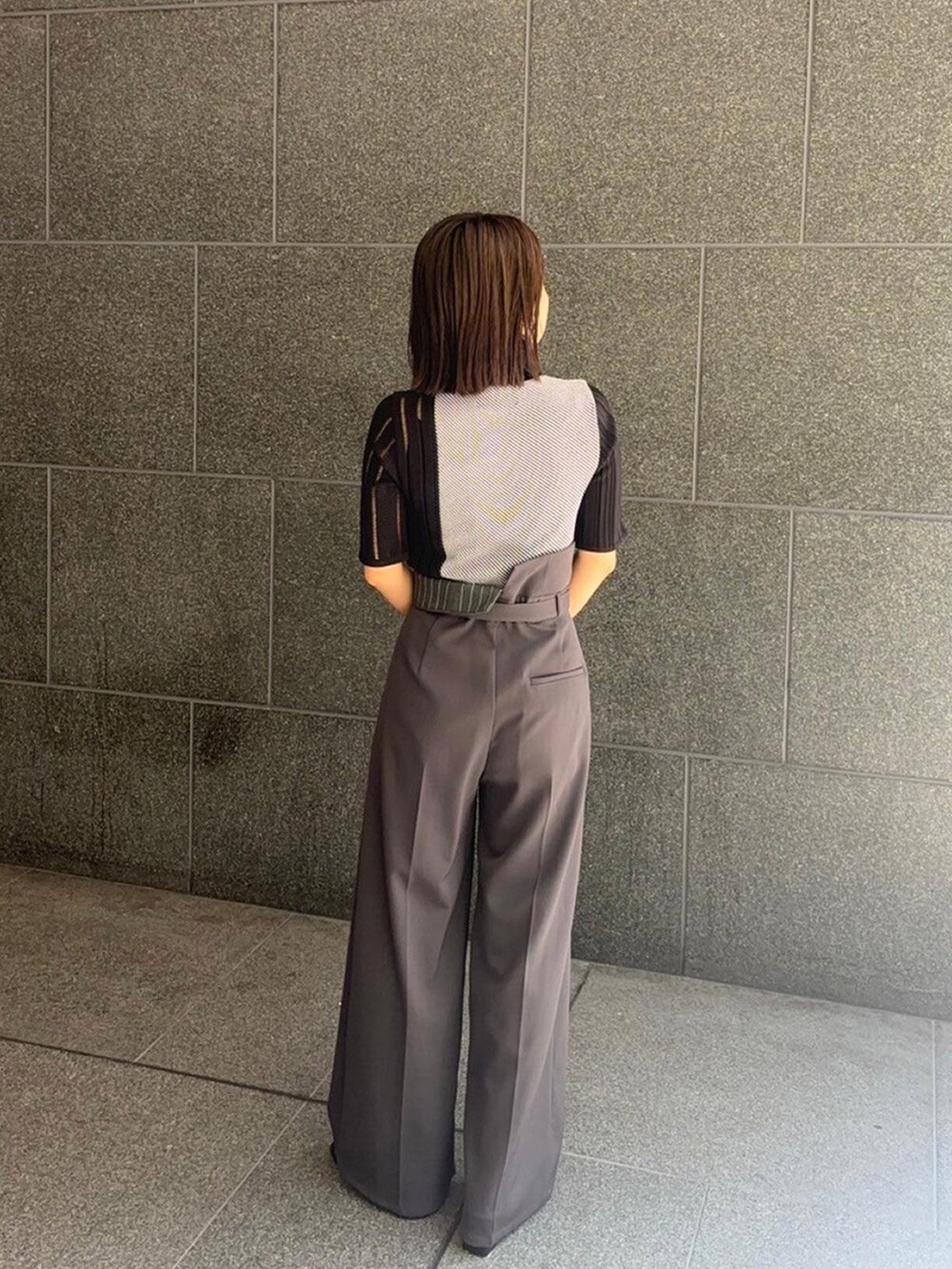 ブラック系のニット/セーター、グレー系のスラックスを着用したレディースの秋コーディネートの3枚目の写真