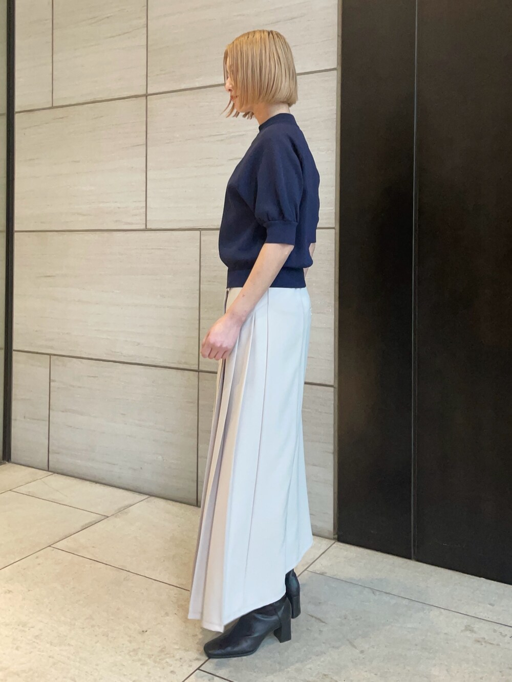 ブルー系のニット/セーター、ベージュ系のスカートを着用したレディースの春コーディネートの2枚目の写真