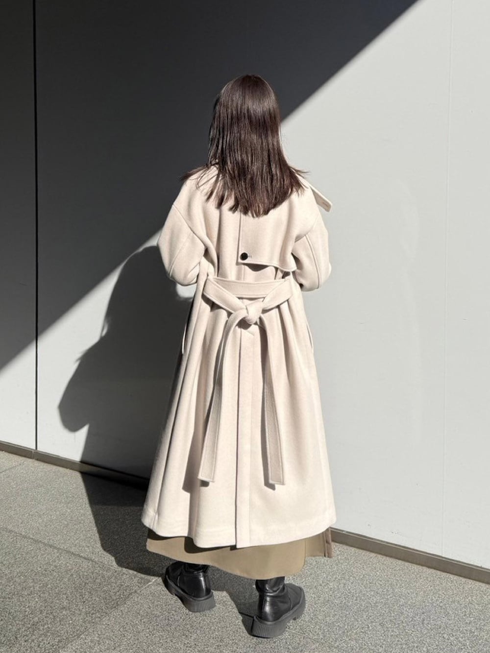 ホワイト系のステンカラーコートを着用したレディースの秋コーディネートの3枚目の写真