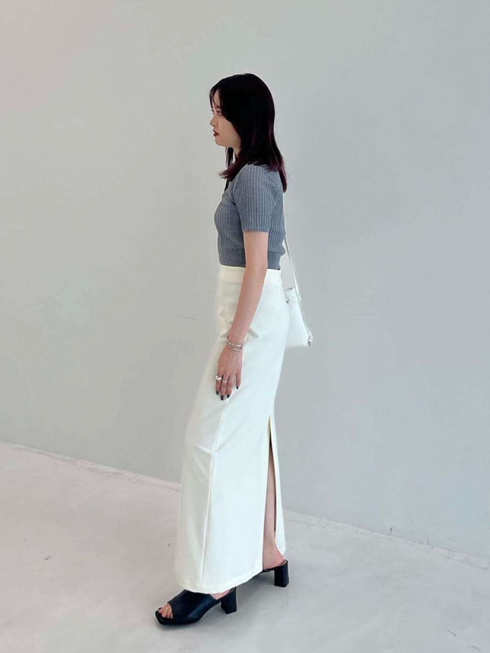 グレー系のポロシャツ、ホワイト系のスカートを着用したレディースの夏コーディネートの2枚目の写真