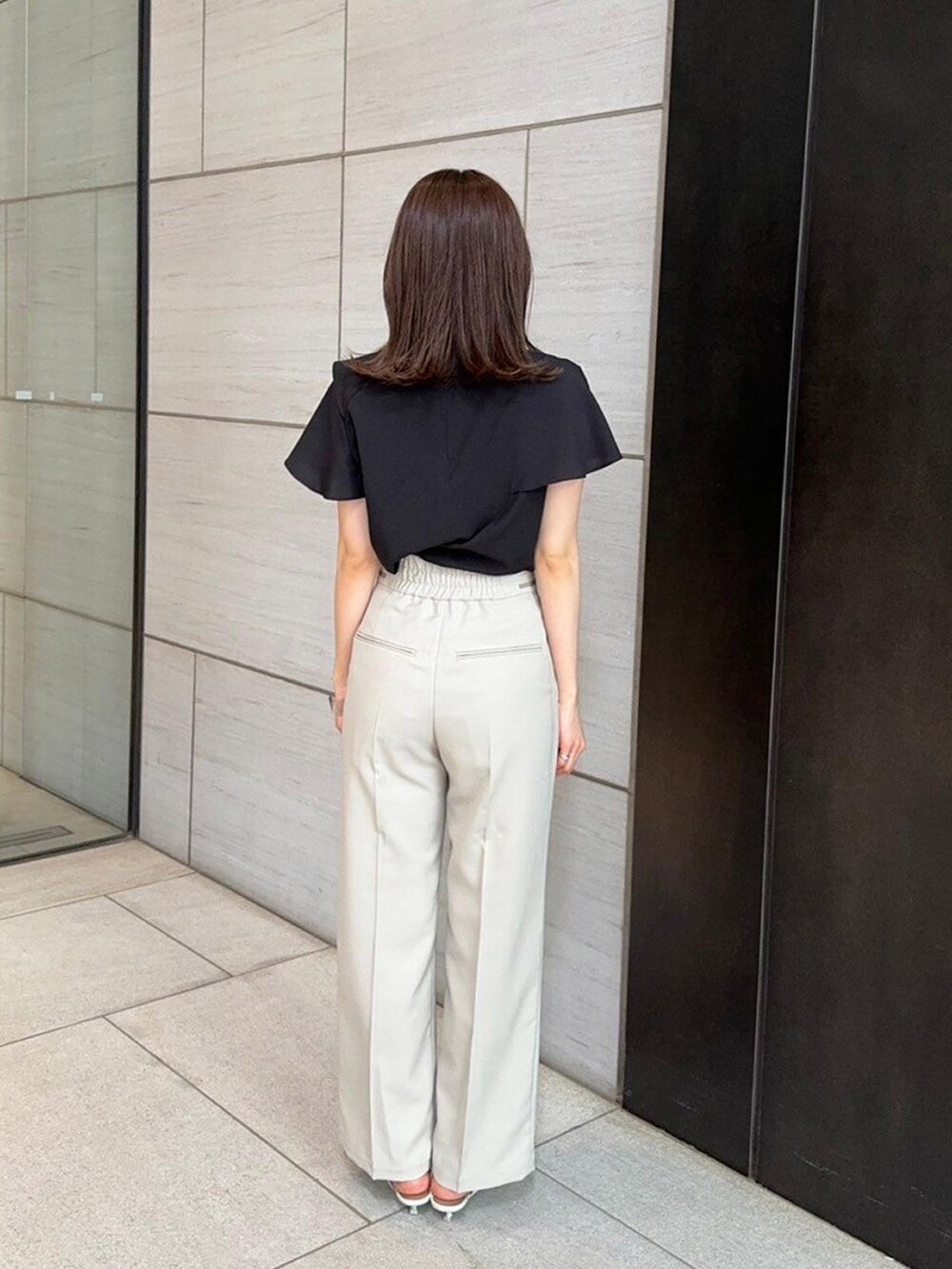 ブラック系のシャツ/ブラウス、ベージュ系のスラックスを着用したレディースの春コーディネートの3枚目の写真