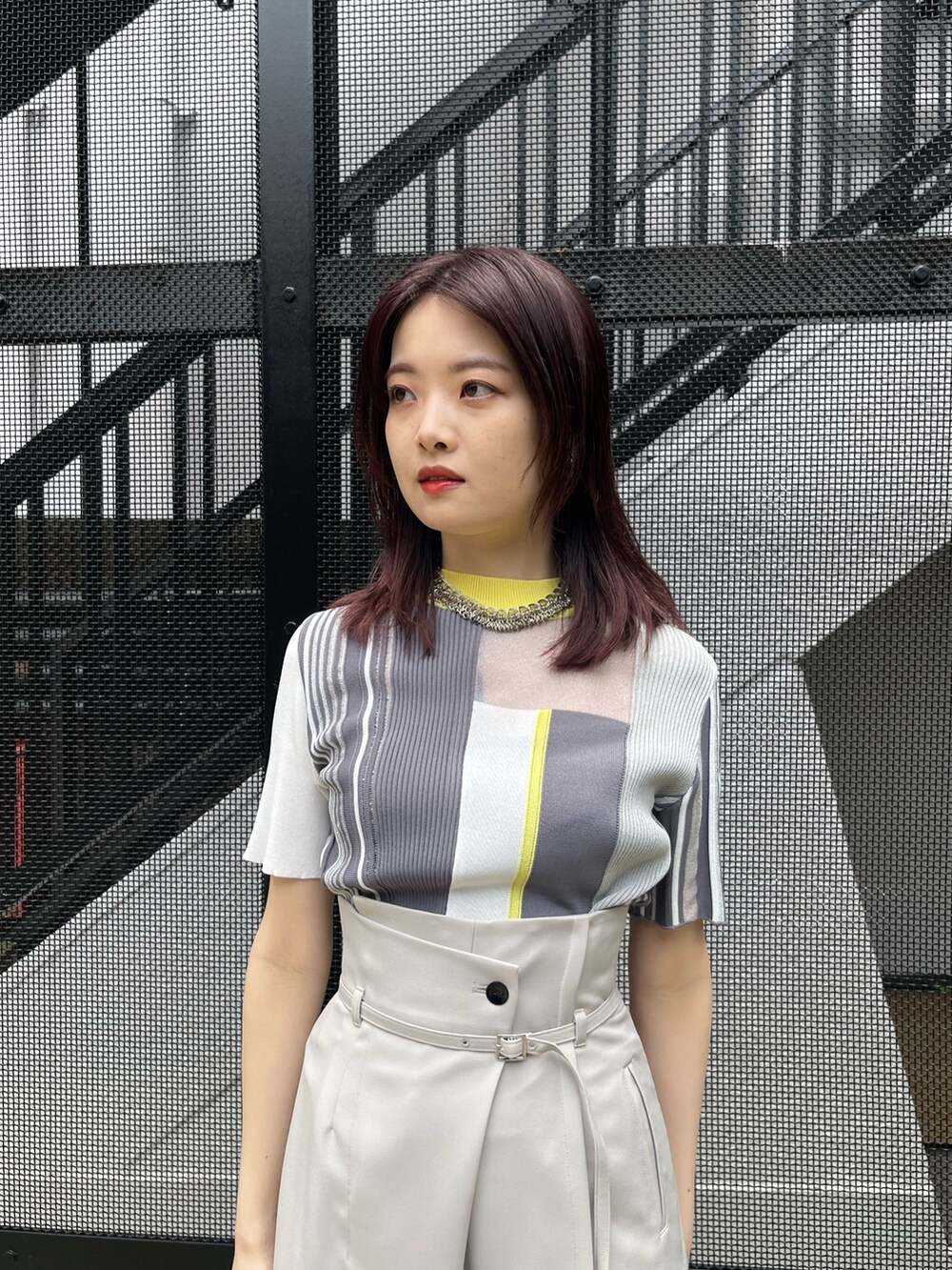 イエロー系のニット/セーター、グレー系のスラックスを着用したレディースの春コーディネートの5枚目の写真