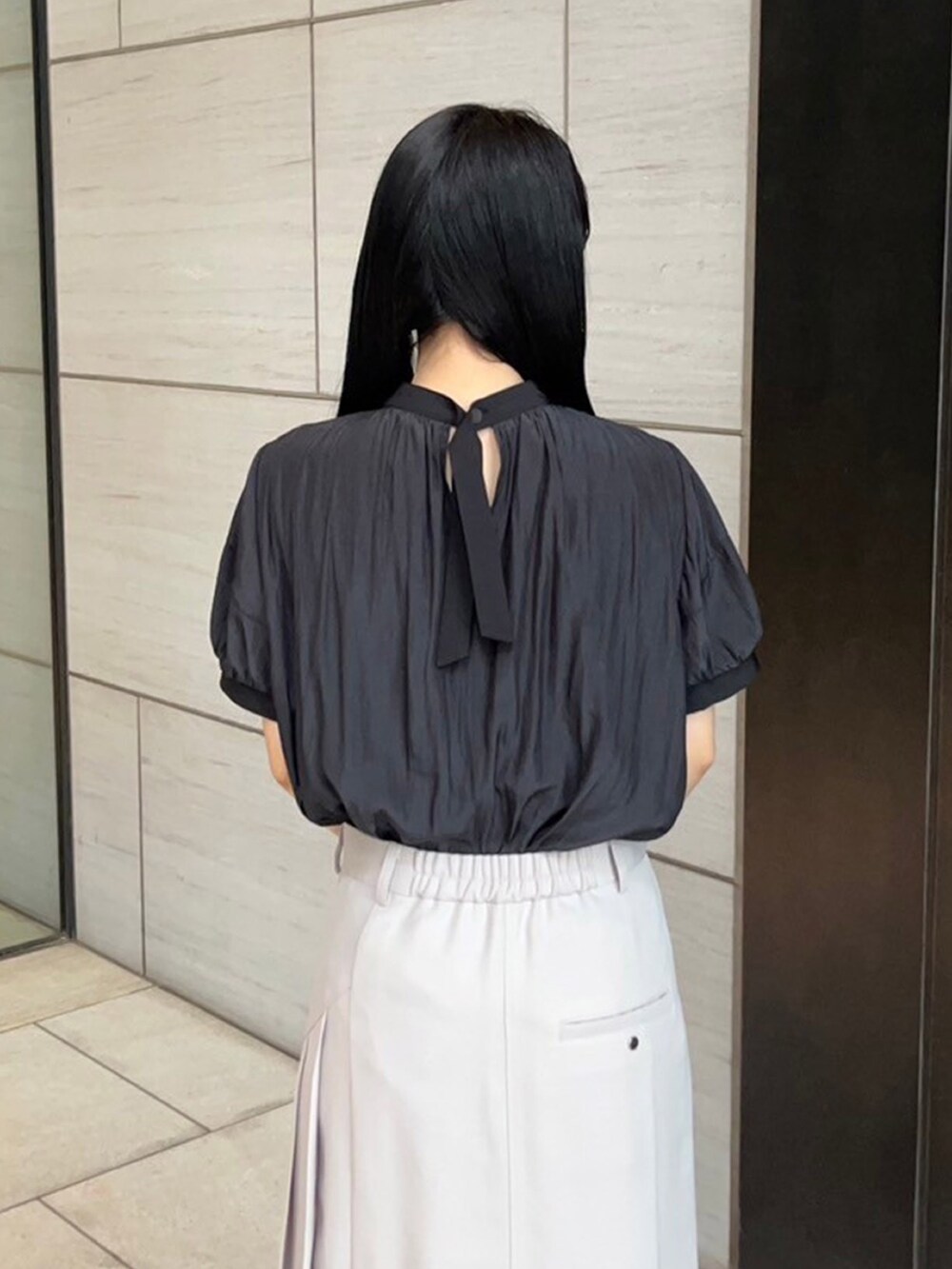 ベージュ系のスカート、ブラック系のシャツ/ブラウスを着用したレディースの春コーディネートの6枚目の写真