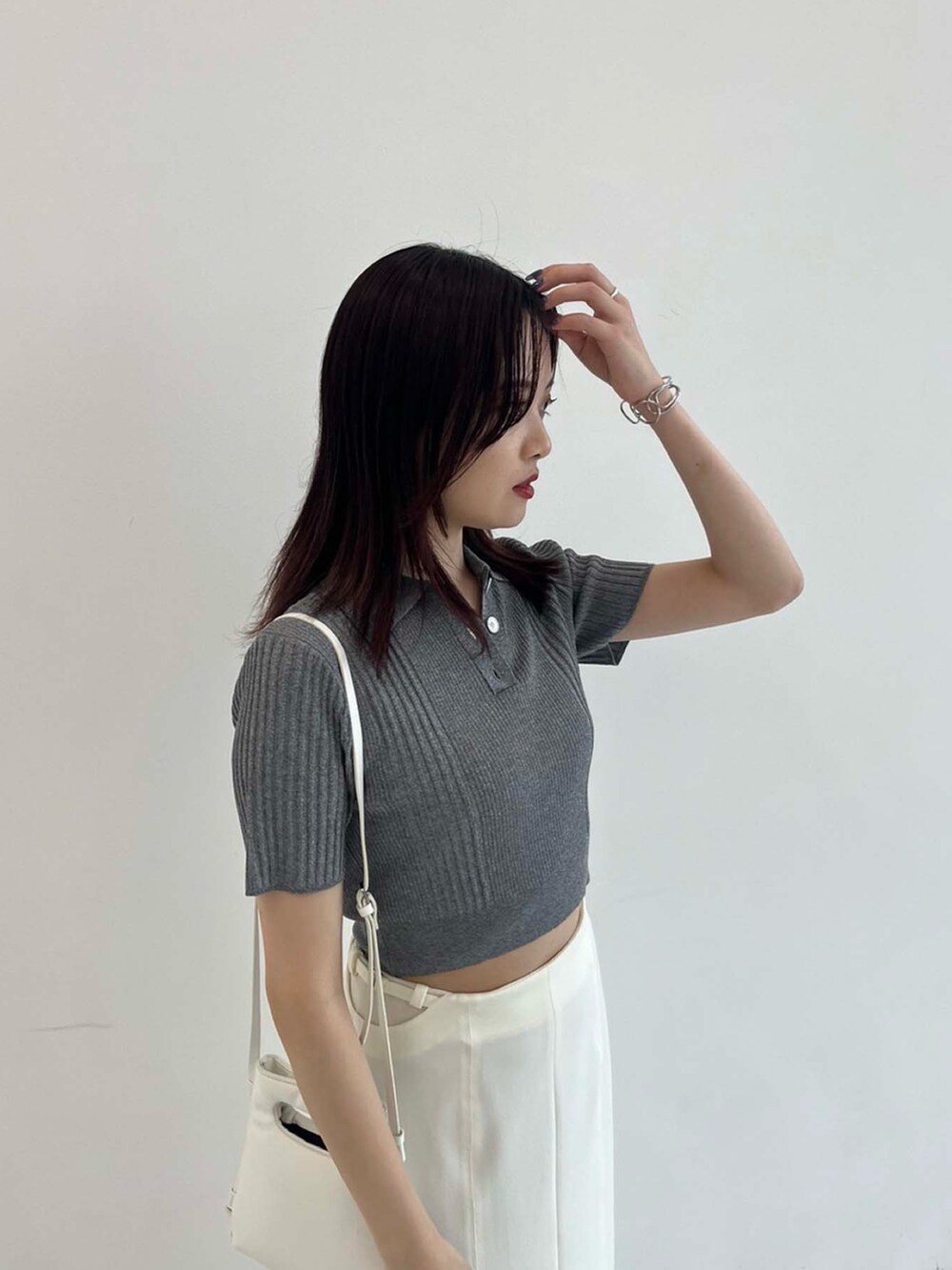 グレー系のポロシャツ、ホワイト系のスカートを着用したレディースの夏コーディネートの4枚目の写真