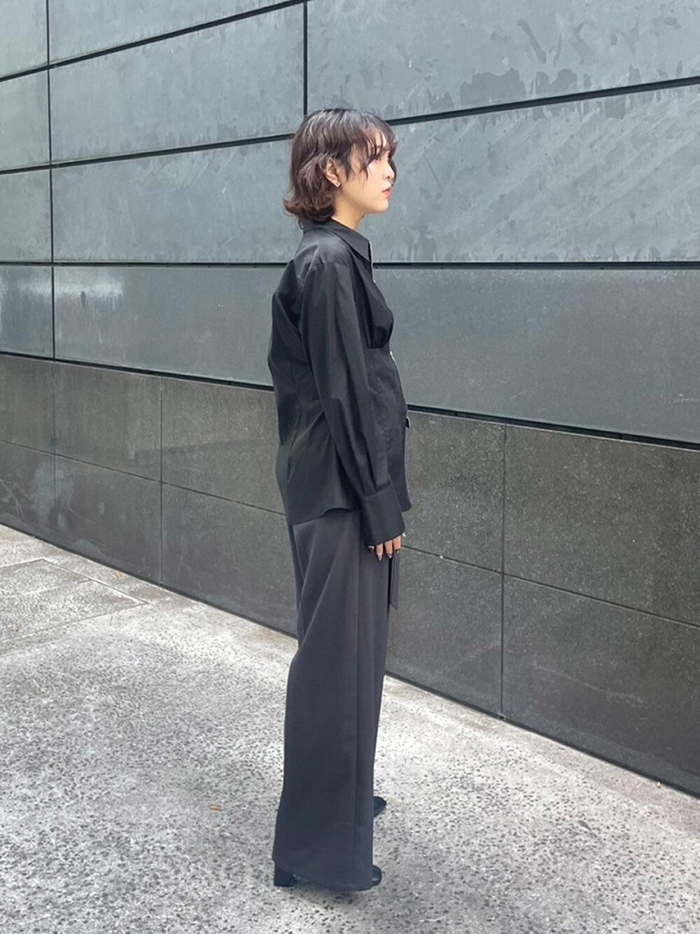 ブラック系のシャツ/ブラウス、グレー系のスラックスを着用したレディースの秋コーディネートの2枚目の写真