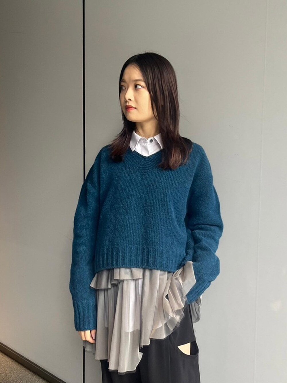 ブルー系のニット/セーター、グレー系のシャツ/ブラウスを着用したレディースの秋コーディネートの3枚目の写真