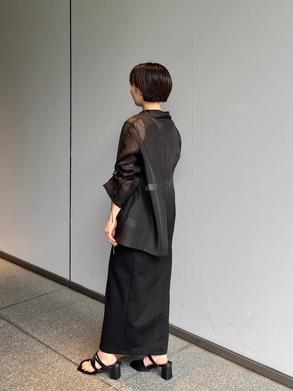 ブラック系のスカート、ブラック系のテーラードジャケットを着用したレディースの夏コーディネートの2枚目の写真