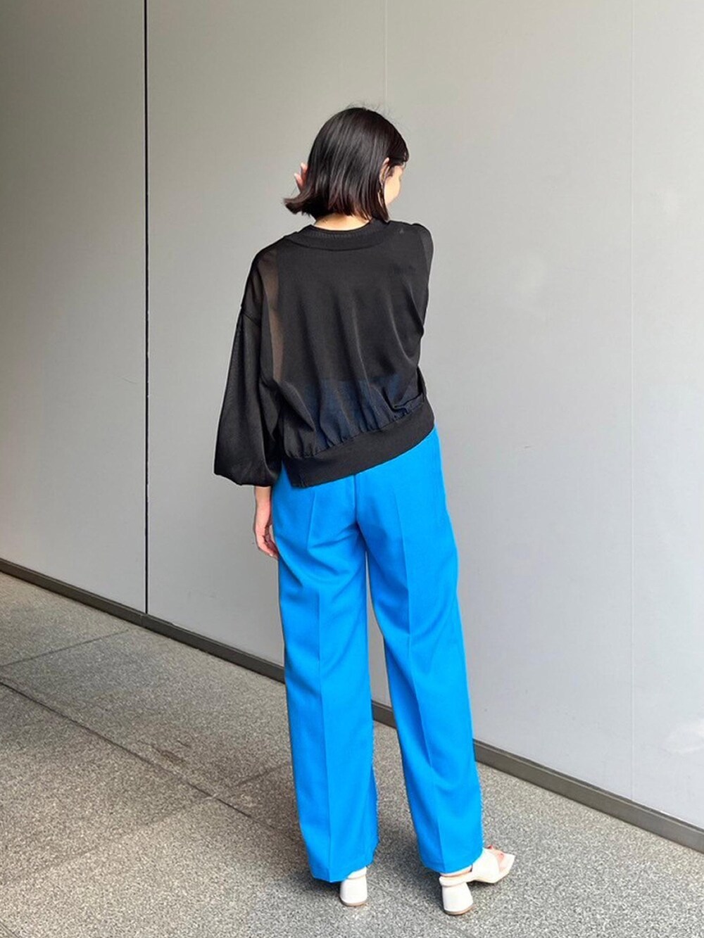 ブラック系のタンクトップ、ブラック系のカーディガン/ボレロ、ブルー系のスラックスを着用したレディースの夏コーディネートの3枚目の写真