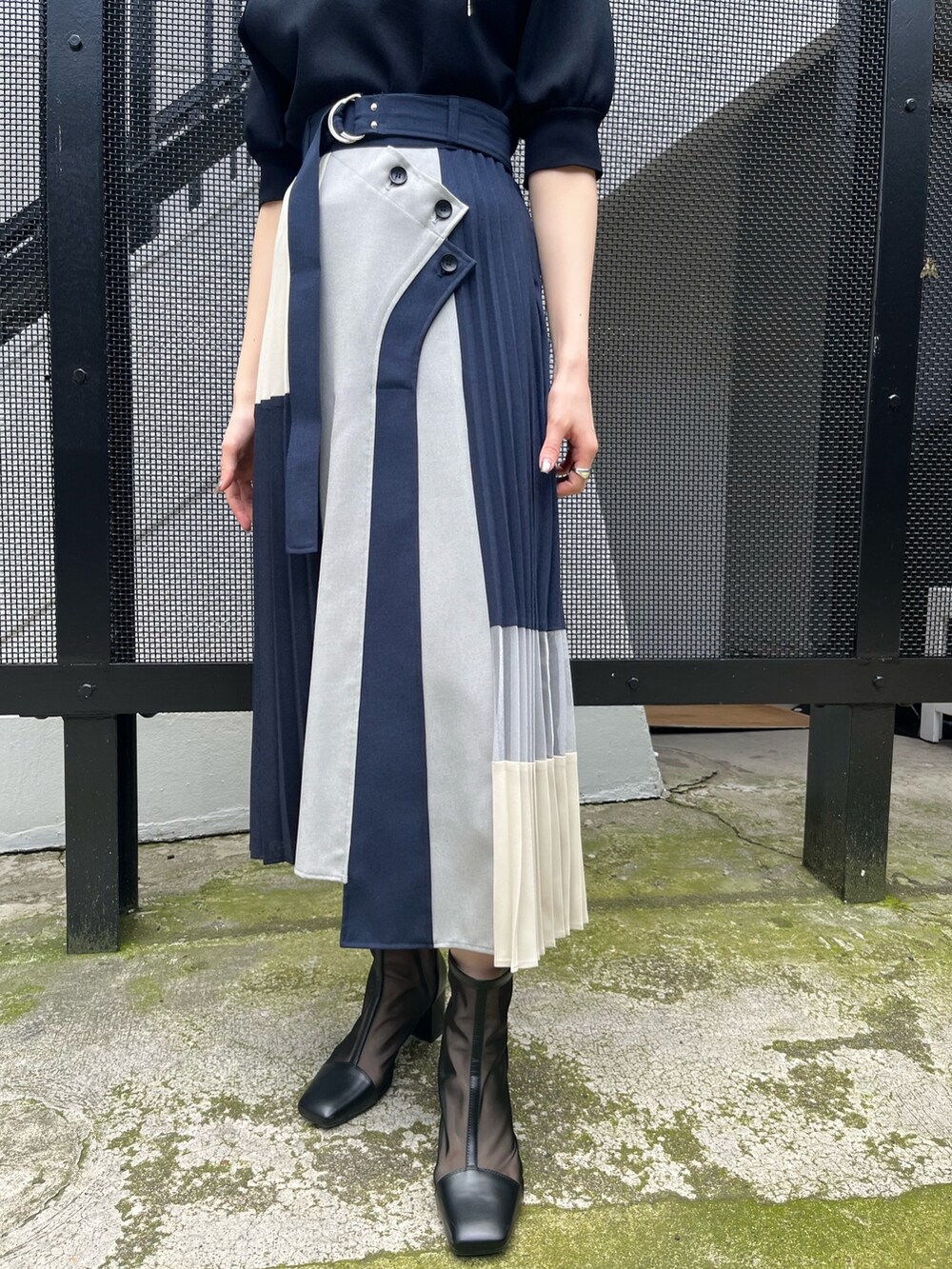 ブラック系のニット/セーター、ブルー系のスカート、ブラック系のブーツを着用したレディースの春コーディネートの5枚目の写真