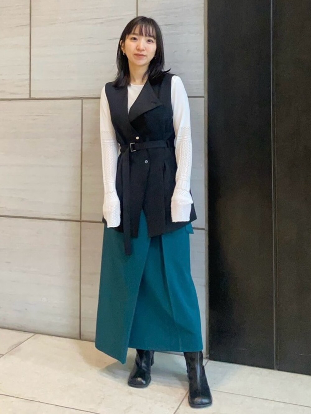 ホワイト系のニット/セーター、ブラック系のベスト、グリーン系のスカートを着用したレディースの春コーディネートの2枚目の写真