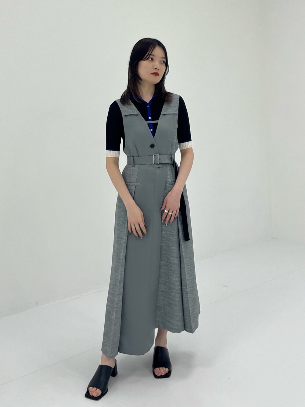 グレー系のジャンパースカート、ブラック系のニット/セーターを着用したレディースの夏コーディネートの2枚目の写真