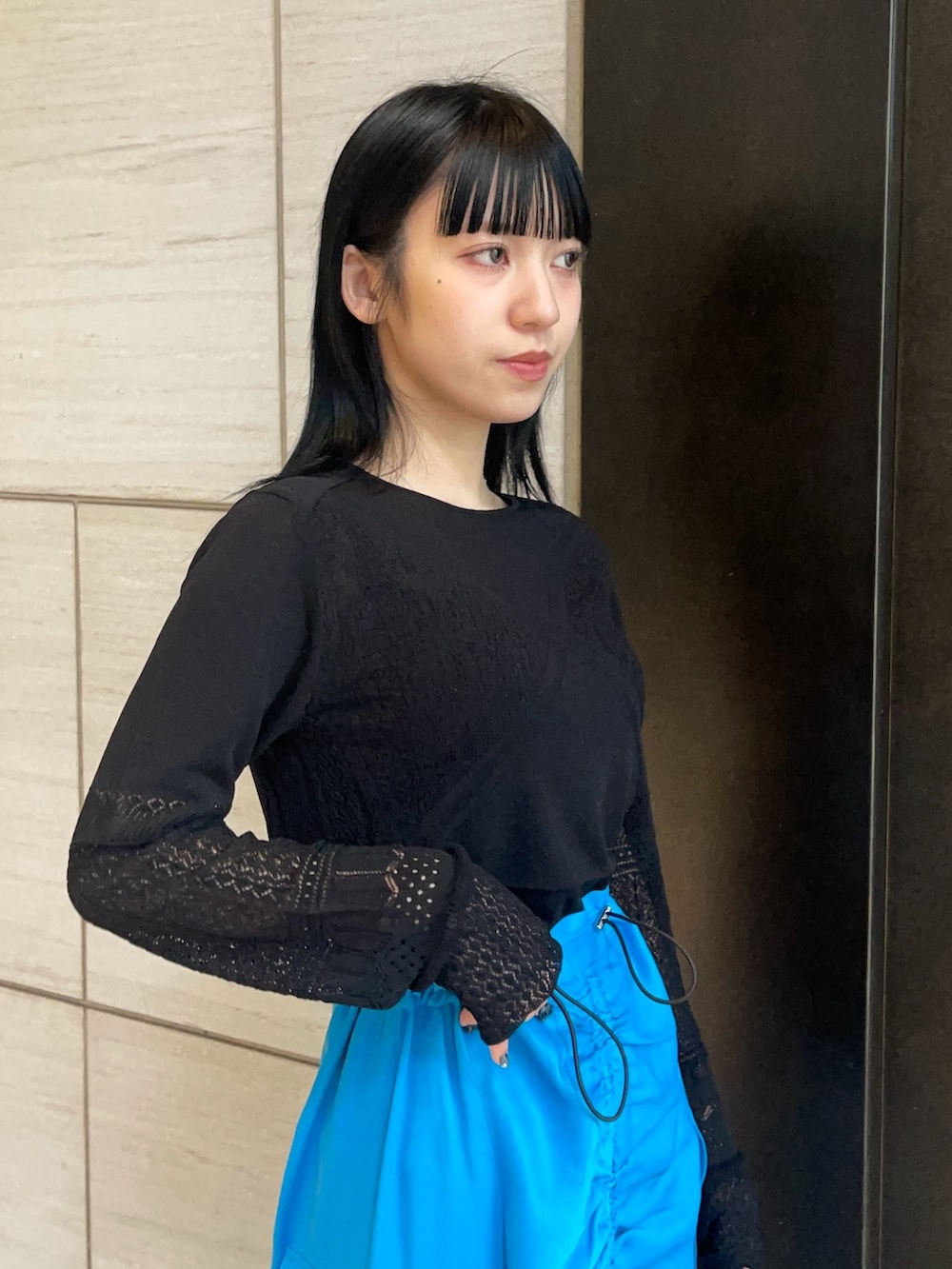 ブラック系のニット/セーター、ブルー系のスカートを着用したレディースの春コーディネートの5枚目の写真