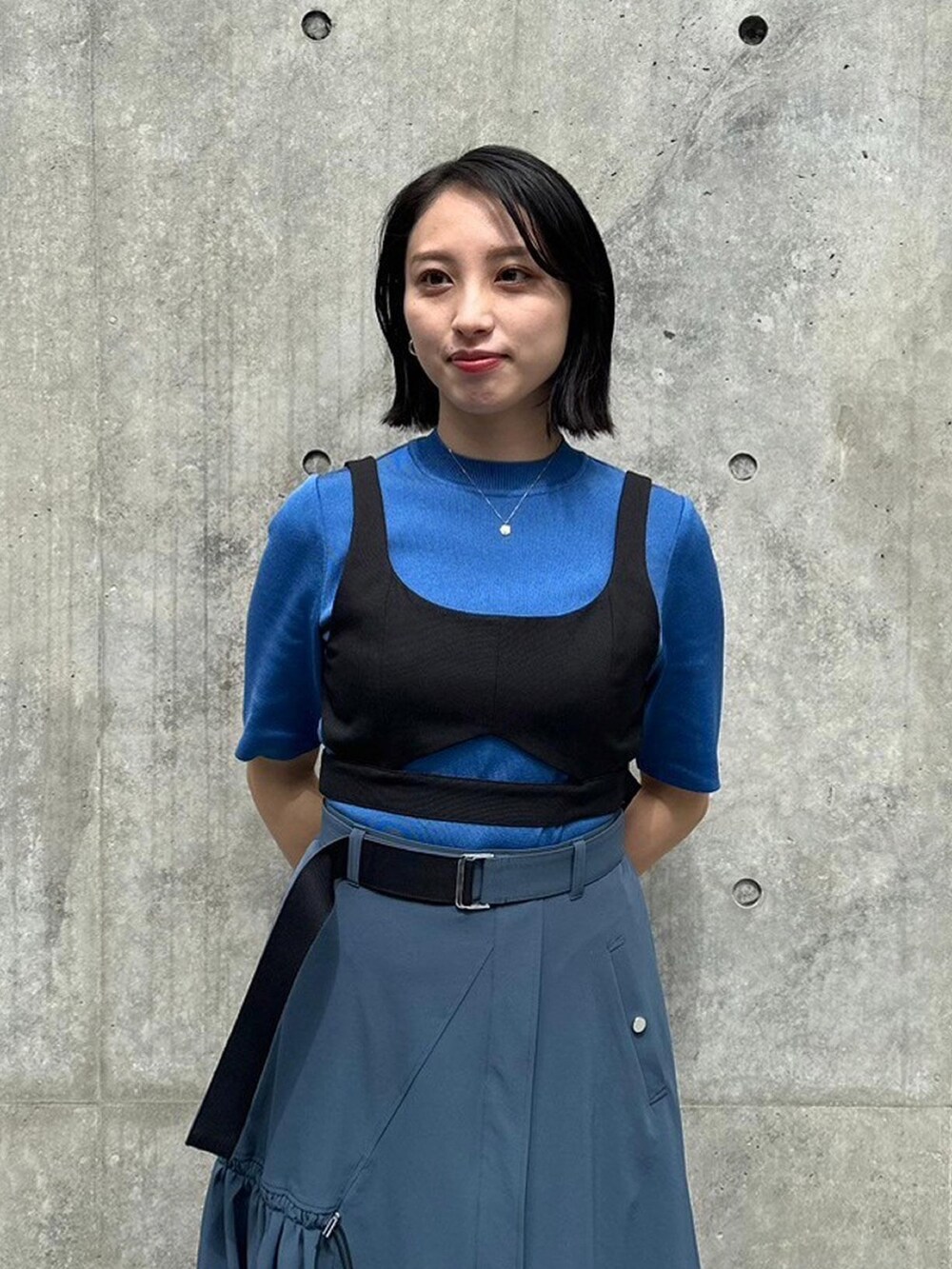 ブルー系のニット/セーター、ブラック系のベスト、グレー系のスカートを着用したレディースの春コーディネートの5枚目の写真