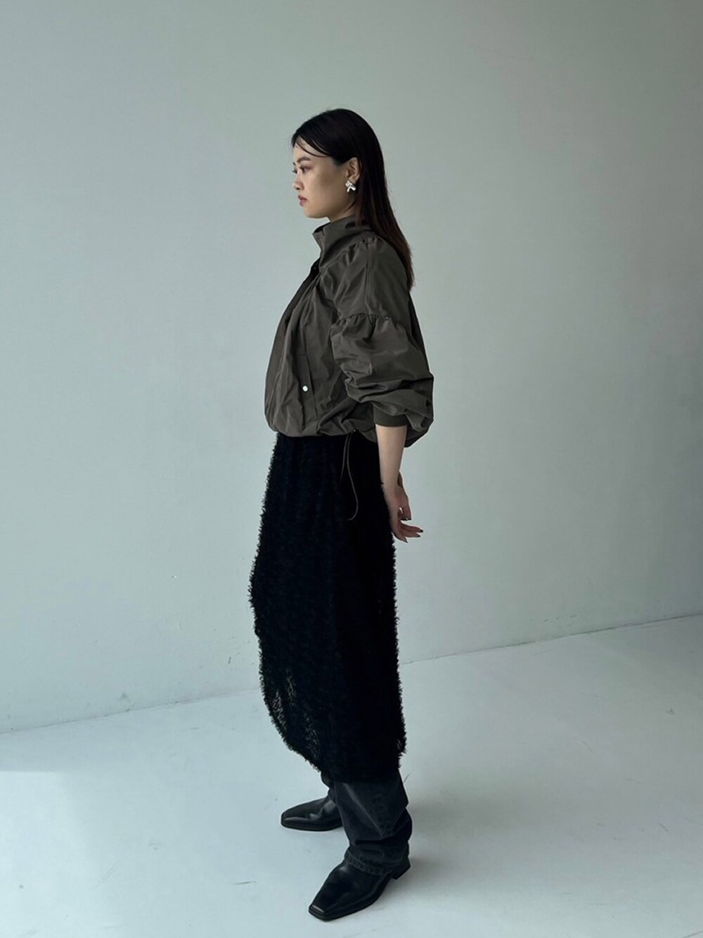 ブラウン系のブルゾン、ブラック系のスカートを着用したレディースの秋コーディネートの2枚目の写真