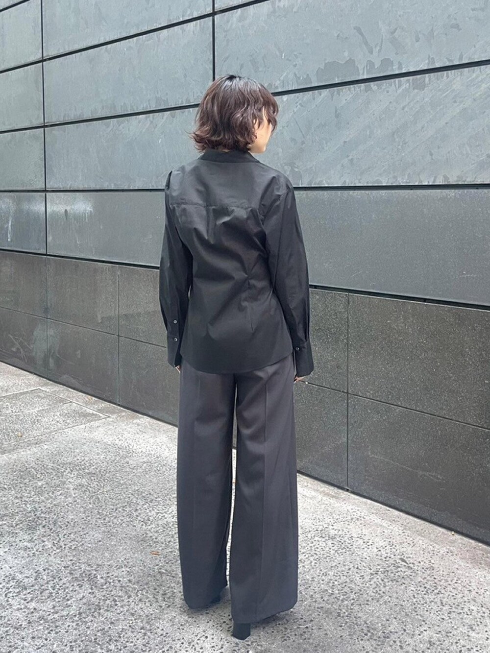 ブラック系のシャツ/ブラウス、グレー系のスラックスを着用したレディースの秋コーディネートの3枚目の写真