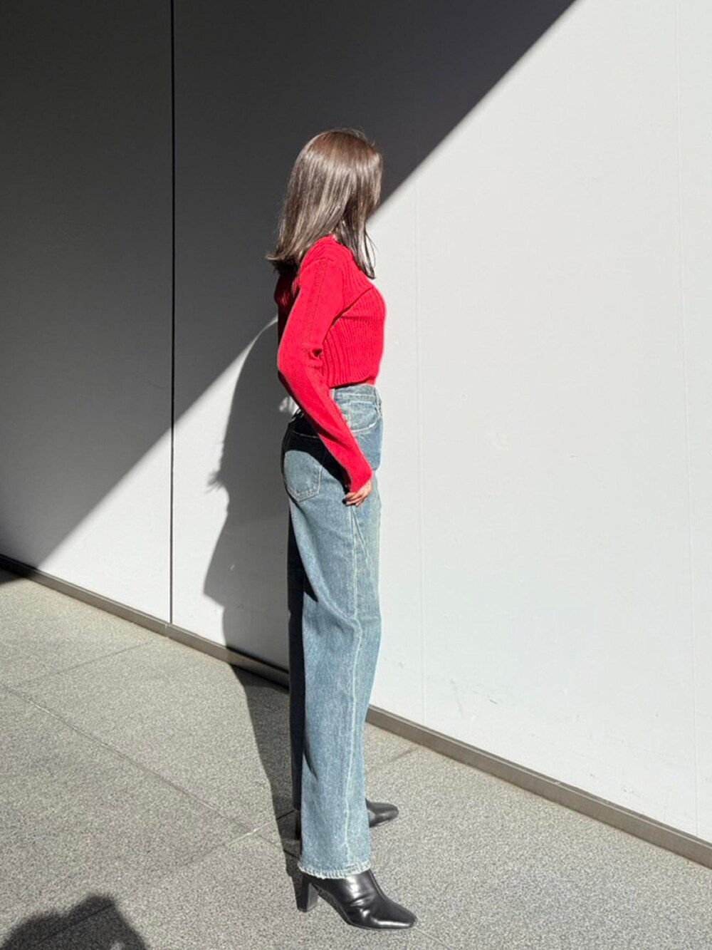 レッド系のニット/セーター、ブルー系のデニムパンツを着用したレディースの秋コーディネートの2枚目の写真