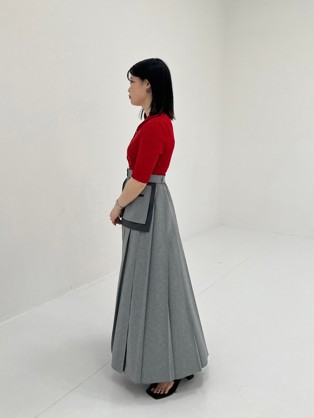 レッド系のニット/セーター、グレー系のスカートを着用したレディースの夏コーディネートの2枚目の写真