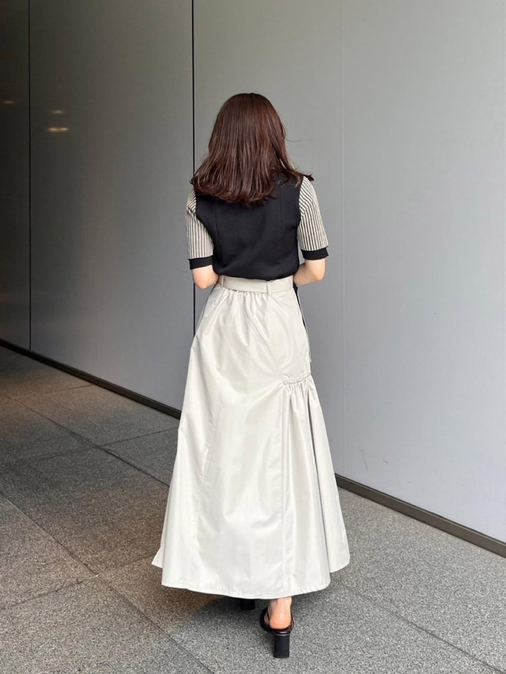 ブラック系のニット/セーター、ベージュ系のスカートを着用したレディースの夏コーディネートの3枚目の写真