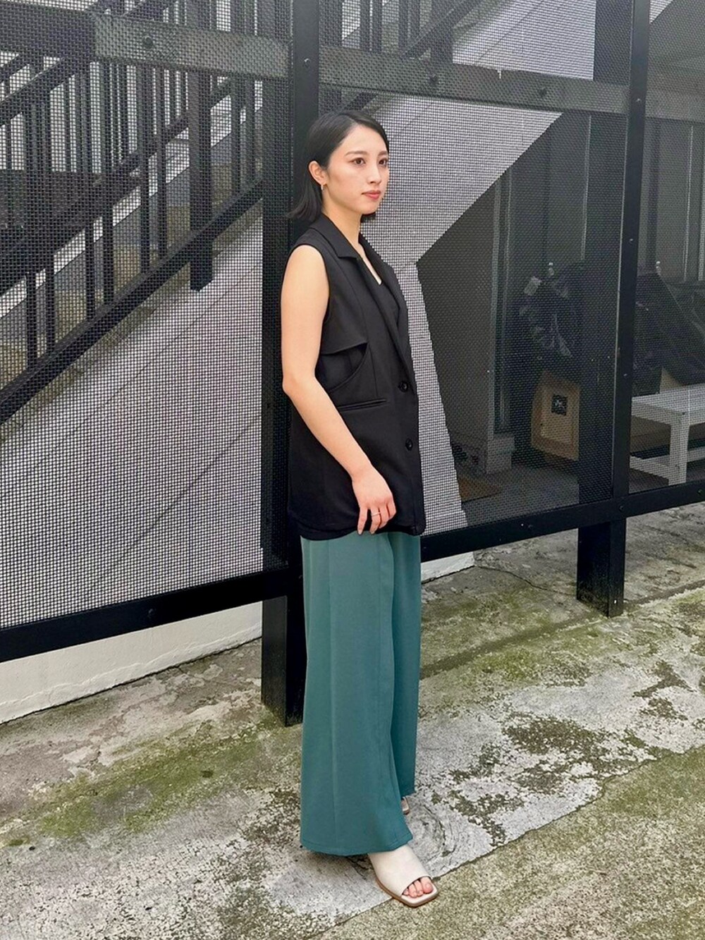 ブラック系のベスト、グリーン系のスラックスを着用したレディースの春コーディネートの4枚目の写真