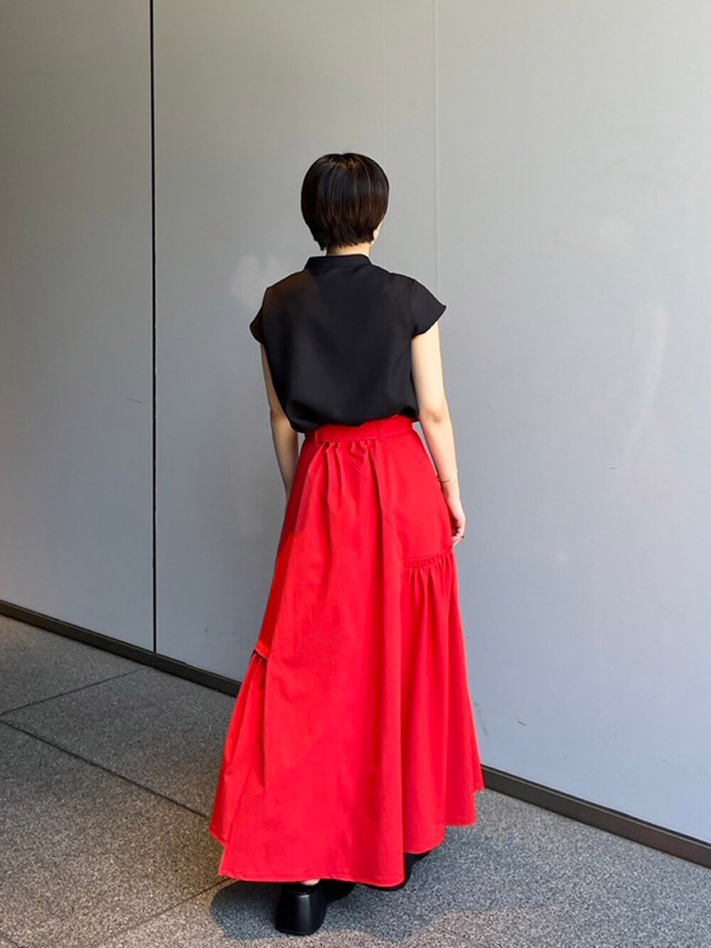 ブラック系のシャツ/ブラウス、レッド系のスカートを着用したレディースの夏コーディネートの2枚目の写真