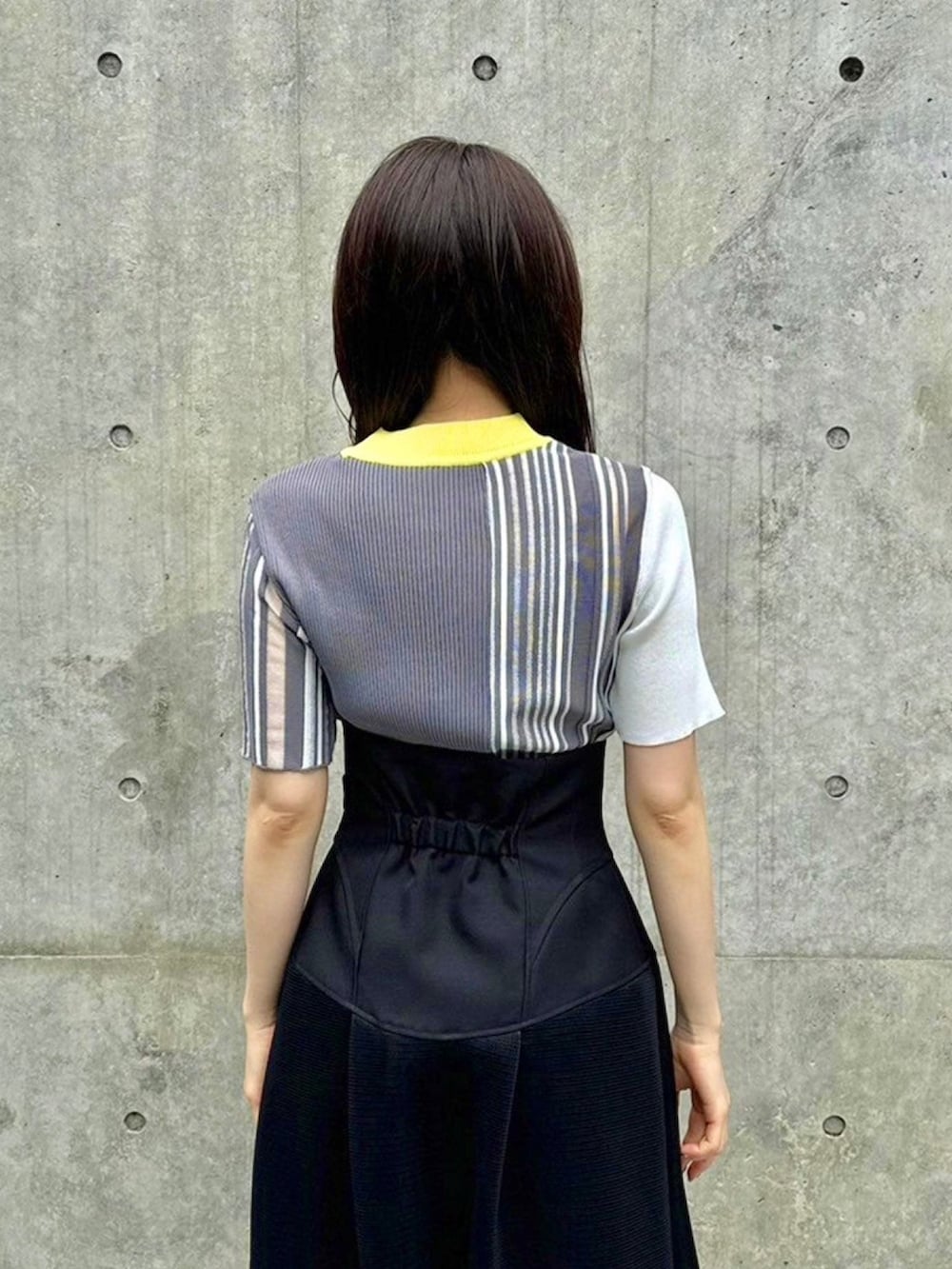 イエロー系のニット/セーター、ブラック系のスカートを着用したレディースの春コーディネートの6枚目の写真