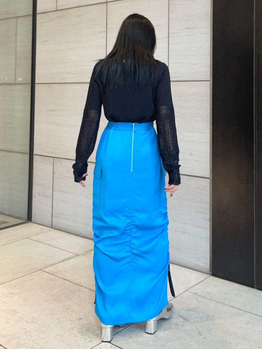 ブラック系のニット/セーター、ブルー系のスカートを着用したレディースの春コーディネートの3枚目の写真