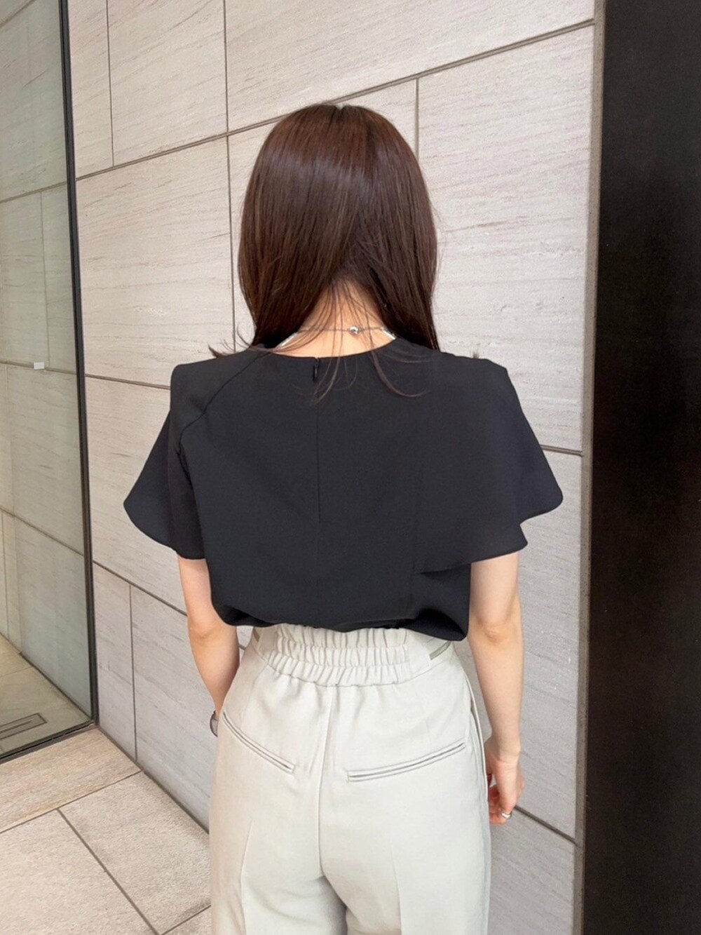 ブラック系のシャツ/ブラウス、ベージュ系のスラックスを着用したレディースの春コーディネートの6枚目の写真