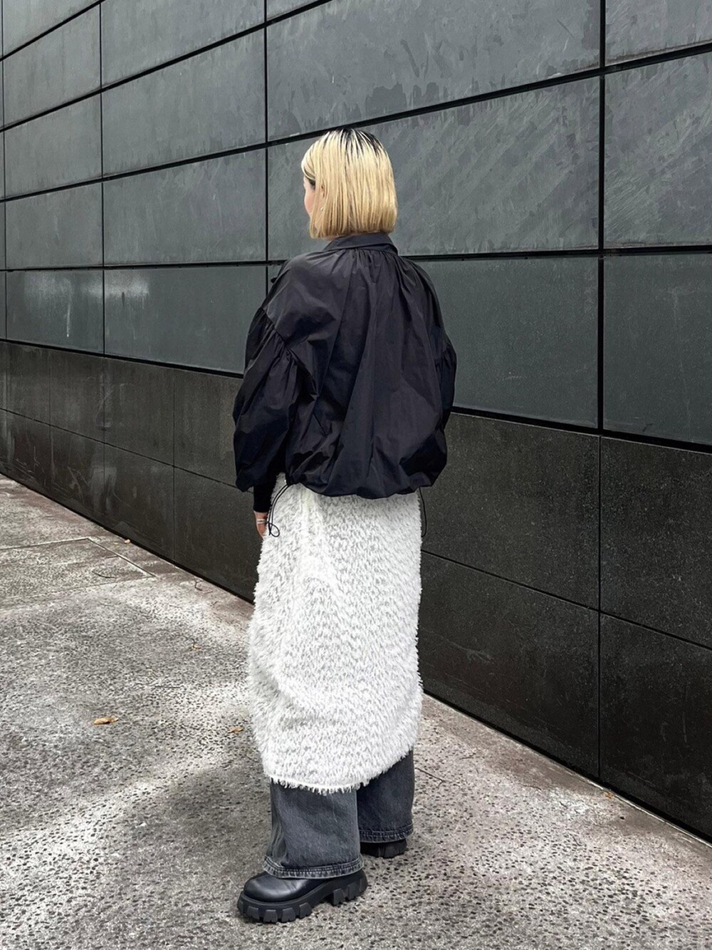 ブラック系のブルゾン、ホワイト系のスカートを着用したレディースの秋コーディネートの3枚目の写真