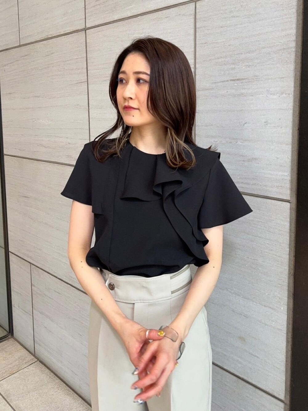 ブラック系のシャツ/ブラウス、ベージュ系のスラックスを着用したレディースの春コーディネートの5枚目の写真