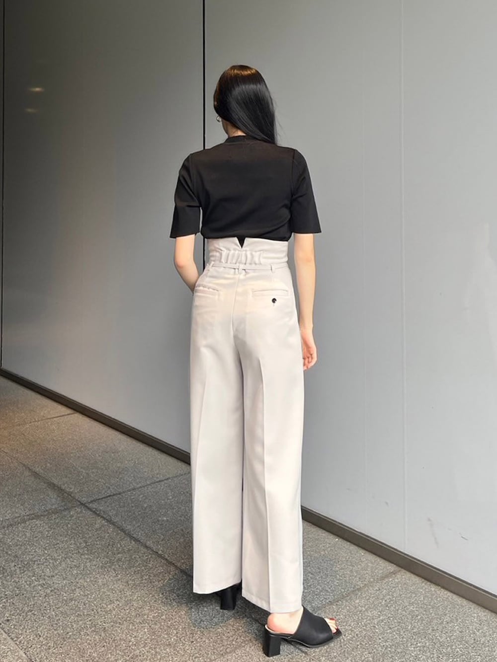 ブラック系のニット/セーター、グレー系のスラックスを着用したレディースの夏コーディネートの3枚目の写真