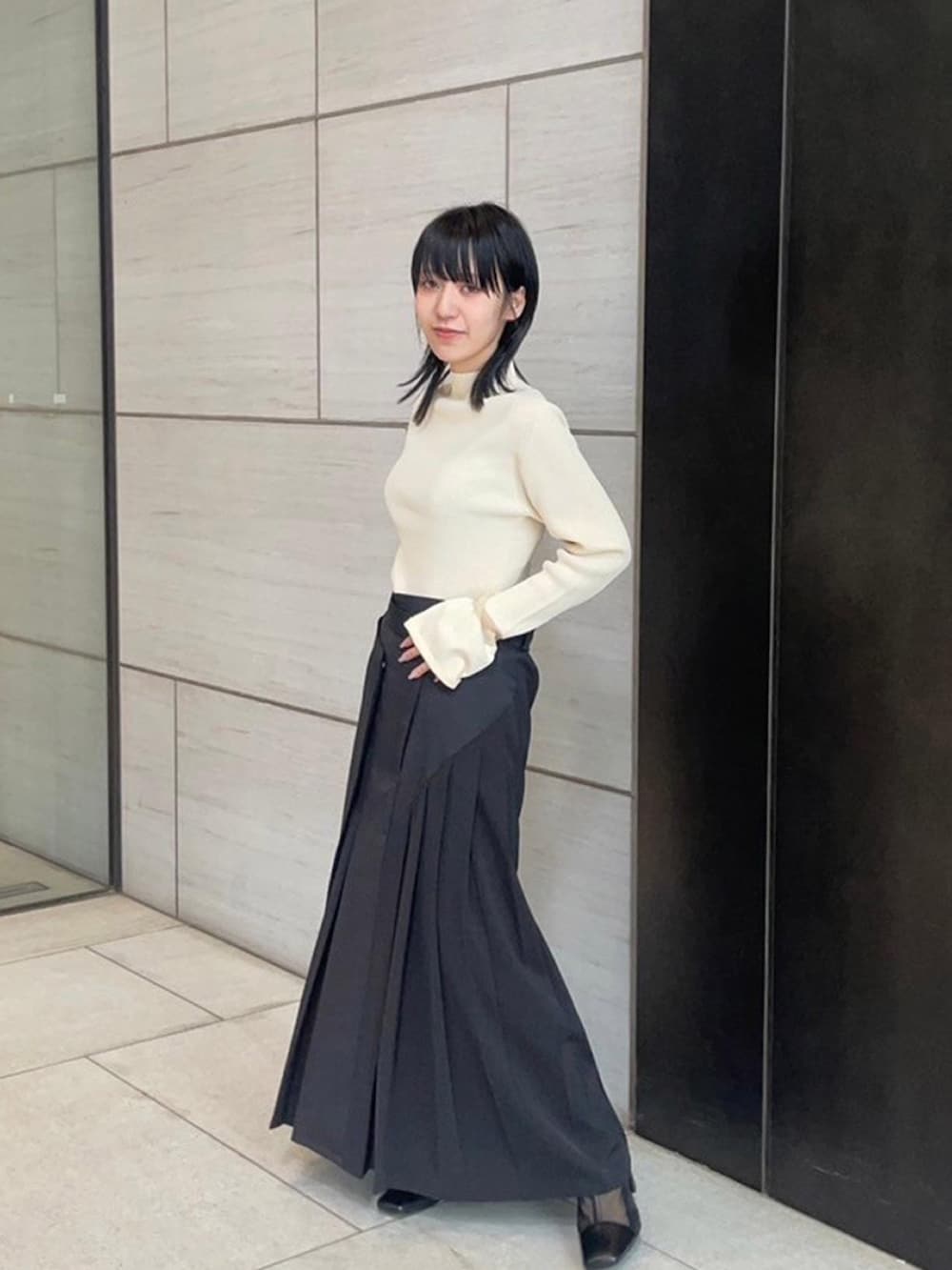 ベージュ系のニット/セーター、ブラック系のスカートを着用したレディースの春コーディネートの2枚目の写真