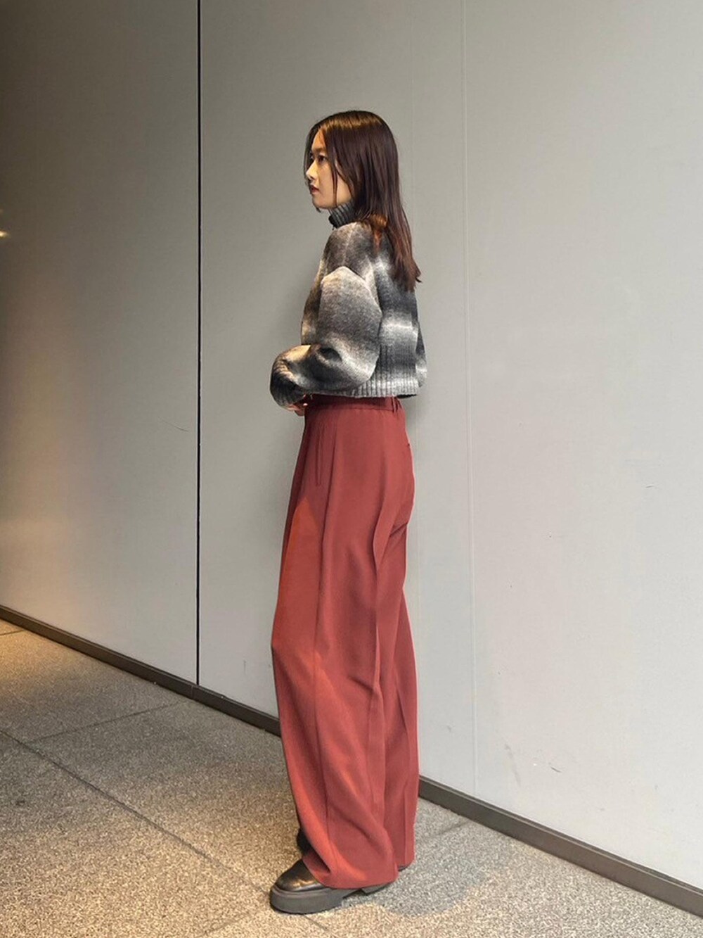 ブラック系のニット/セーター、レッド系のスラックスを着用したレディースの秋コーディネートの2枚目の写真