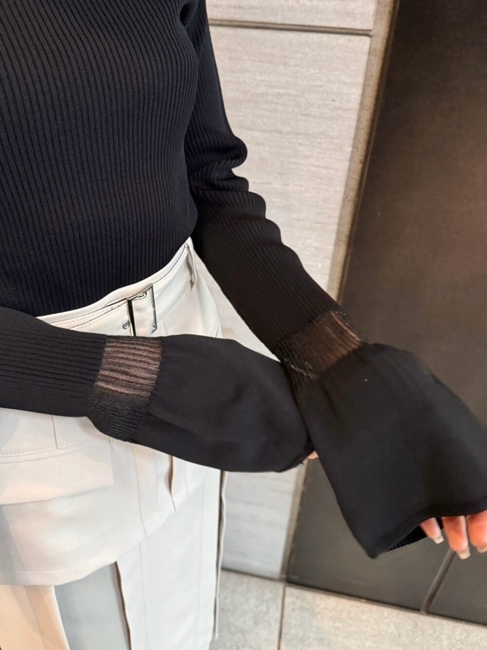 ベージュ系のスカート、ブラック系のニット/セーターを着用したレディースの春コーディネートの9枚目の写真