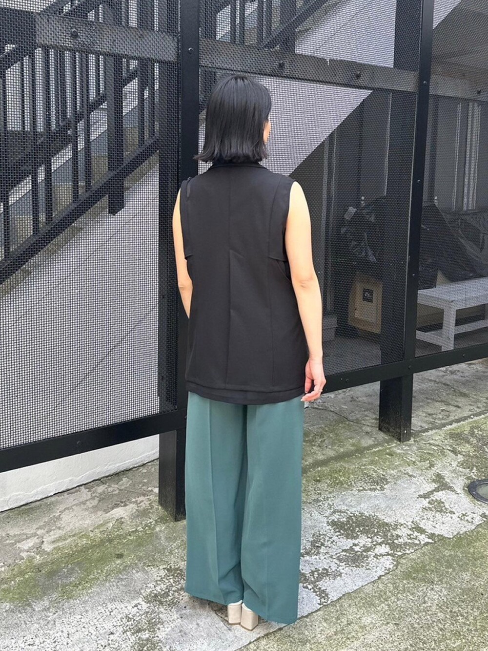 ブラック系のベスト、グリーン系のスラックスを着用したレディースの春コーディネートの3枚目の写真
